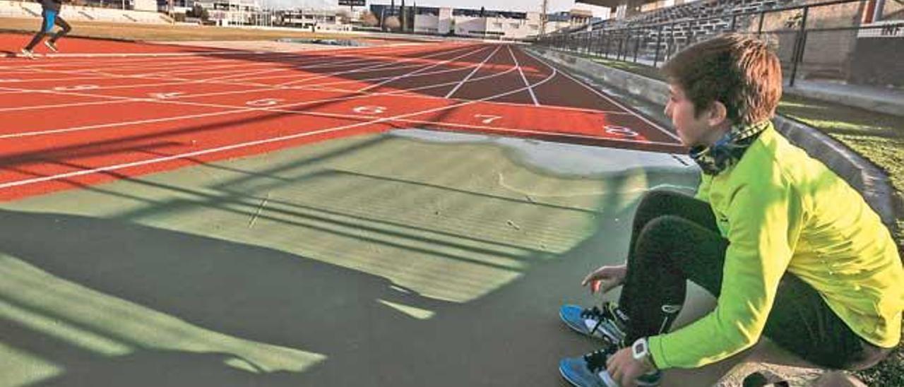 Un niño observa a un atleta sobre la pista de atletismo del Polideportivo Príncipes de España.