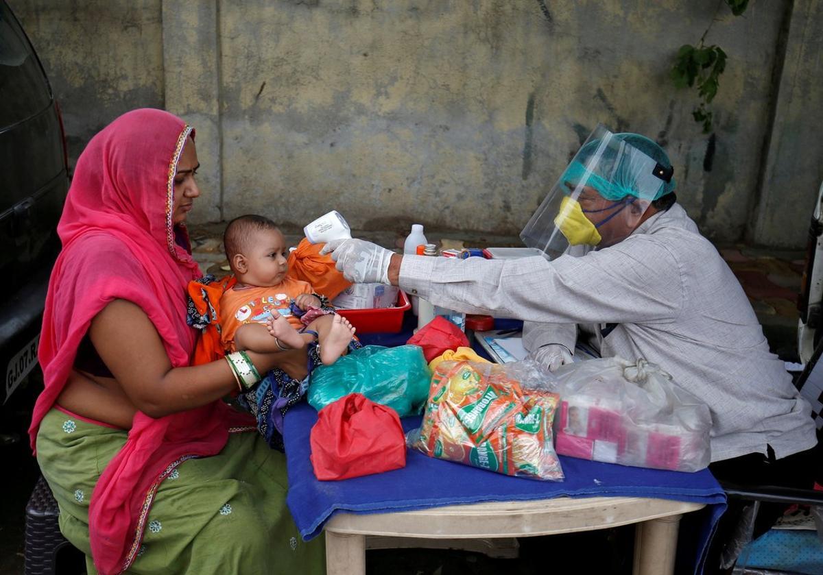 FILE PHOTO: A doctor wearing a protective face shield uses an infrared thermometer to measure the temperature of a child at his mobile health clinic, after his clinic and its adjoining areas were declared a micro-containment zone, after authorities eased lockdown restrictions that were imposed to slow the spread of the coronavirus disease (COVID-19), in Ahmedabad, India, June 15, 2020. REUTERS/Amit Dave/File Photo