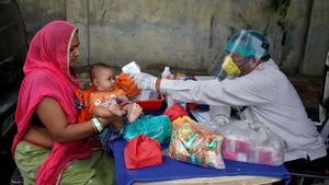 FILE PHOTO: A doctor wearing a protective face shield uses an infrared thermometer to measure the temperature of a child at his mobile health clinic, after his clinic and its adjoining areas were declared a micro-containment zone, after authorities eased lockdown restrictions that were imposed to slow the spread of the coronavirus disease (COVID-19), in Ahmedabad, India, June 15, 2020. REUTERS/Amit Dave/File Photo