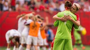 Dos jugadoras canadienses se abrazan, mientras Inglaterra celebra el pase a semis