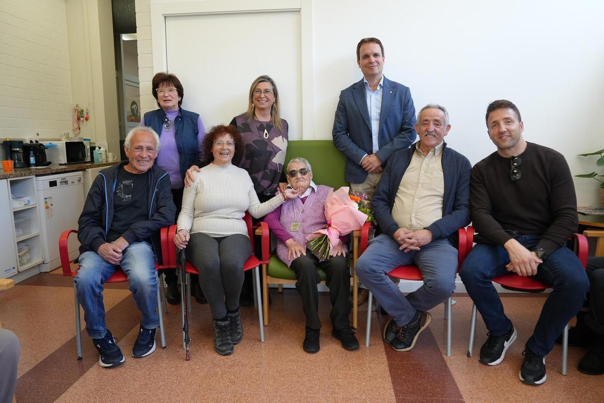 Lola Liceras Arroyo, al centre amb el ram de flors, durant la celebració del seu 100è aniversari amb familiars i representants institucionals a Girona.