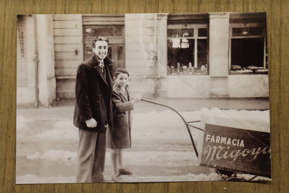 Ismael Migoya, la primera generación de la farmacia de la calle Jovellanos, junto a un niño con el carro de reparto, que llevaba medicamentos por el centro de Oviedo, enfrente de la pastelería Camilo de Blas