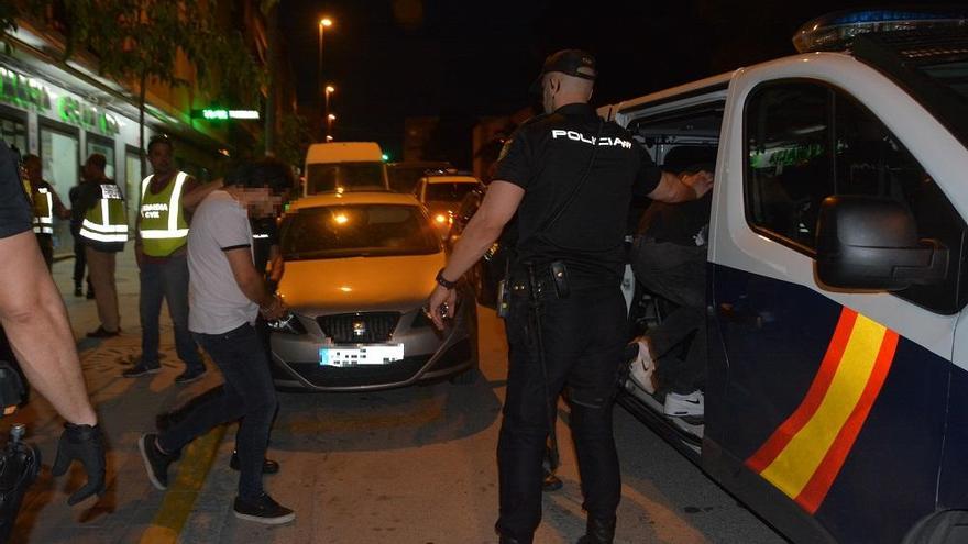 Un sospechoso, esposado, conducido al furgón policial.