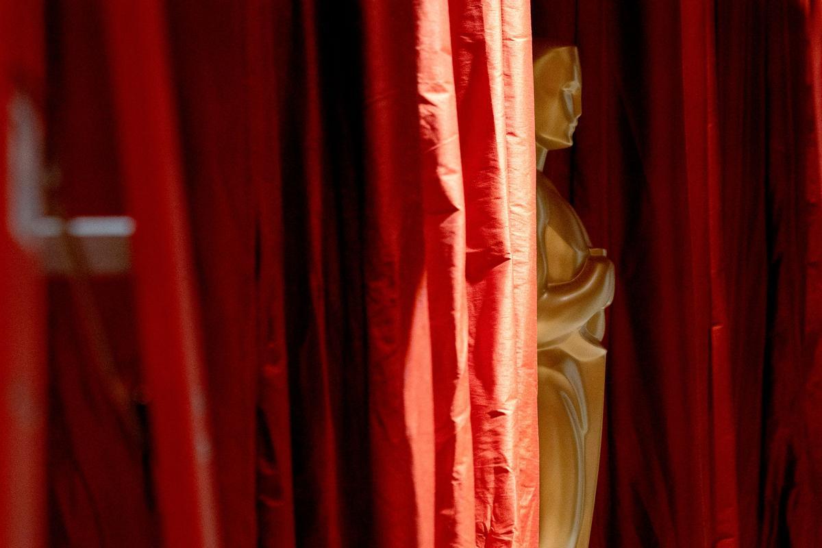 Una réplica decorativa de la estatua del Oscar se encuentra en medio de cortinas rojas en el área de llegadas de la alfombra roja.