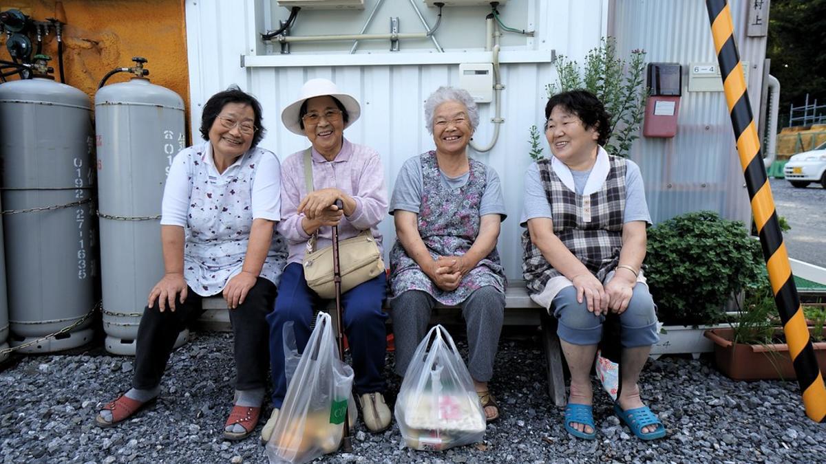 Un grupo de ancianas japonesas sentadas en un banco.