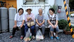 Un grupo de ancianas japonesas sentadas en un banco.