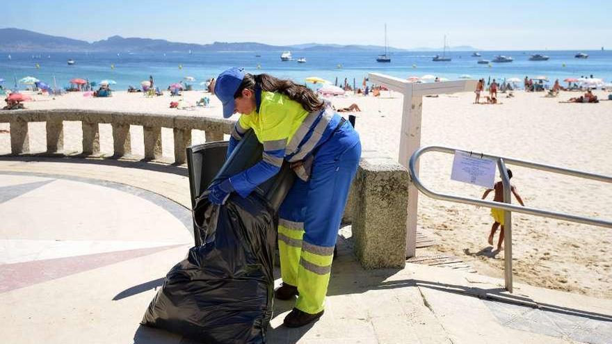 Una operaria recoge la basura de una papelera en el paseo de Silgar // Gustavo Santos