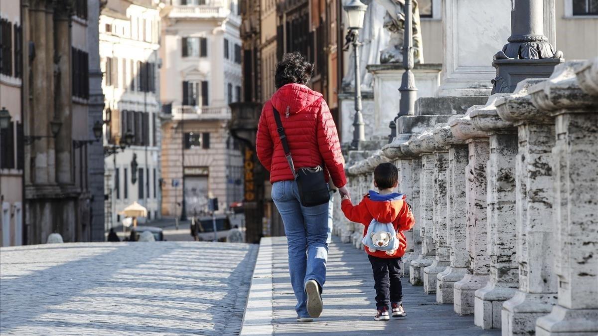 jmexposito53020811 rome  italy   03 04 2020   a woman and a child walk holding 200404110417