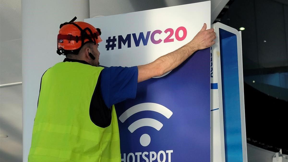 Un trabajador coloca un cartel informativo del Mobile World Congress del 2020