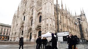 Turistas con mascarillas pasan por delante de la catedral de Milán, en Lombardía.