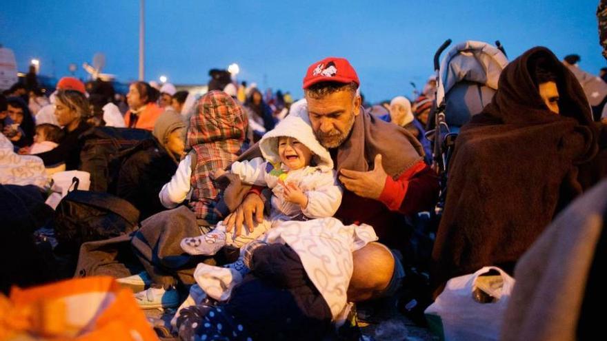 Refugiados esperan por un transporte, tras llegar a la frontera austriaca en autobús desde Hungría.