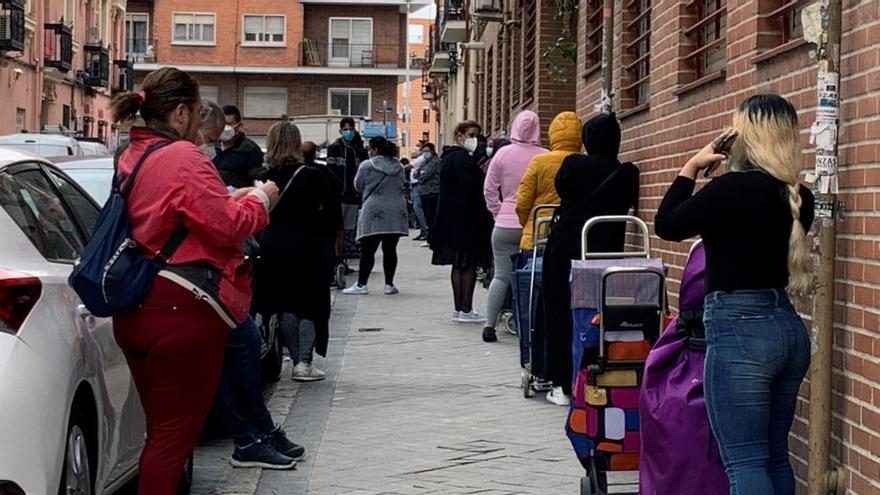 Vista de la fila de clientes que aguardan su turno para entrar al economato de CÃ¡ritas en el distrito madrileÃ±o de TetuÃ¡n.