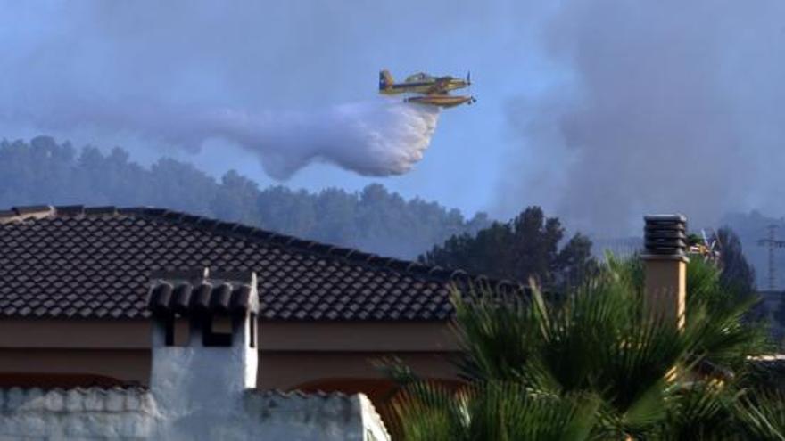 Un hidroavión lanza agua sobre las llamas que asolan el paraje natural de Los Cerros, en Llombai.