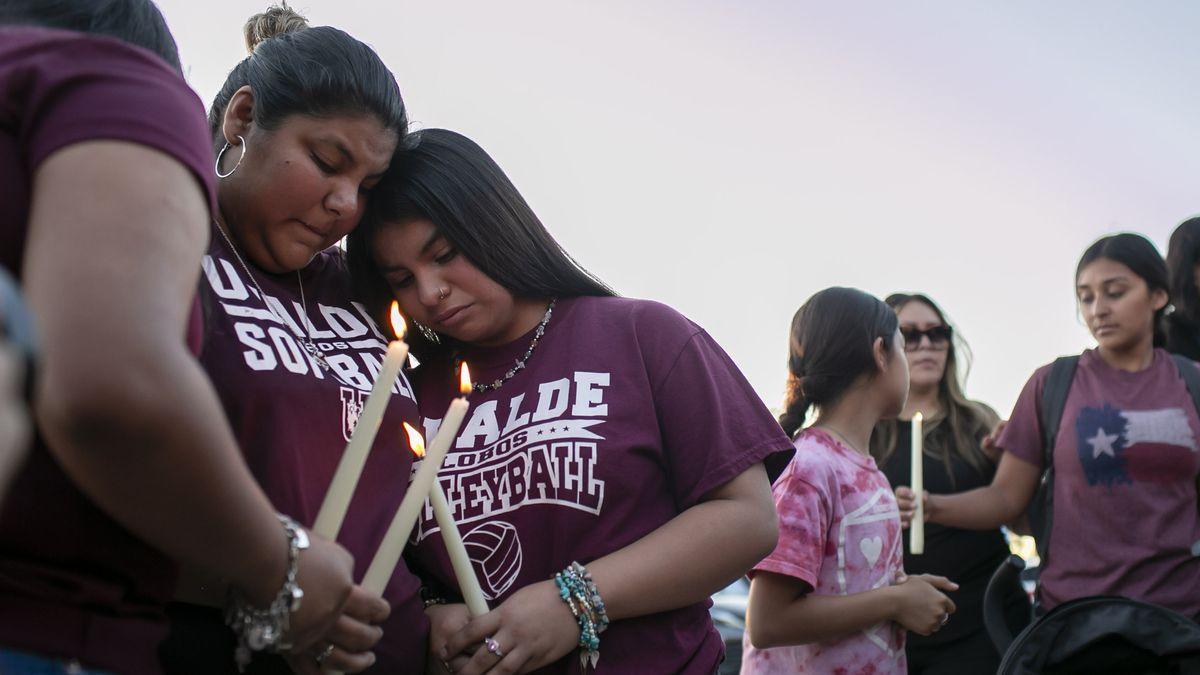 Vecinos de Uvalde se consuelan durante una vigilia con velas celebrada en el Fairplex Arena.