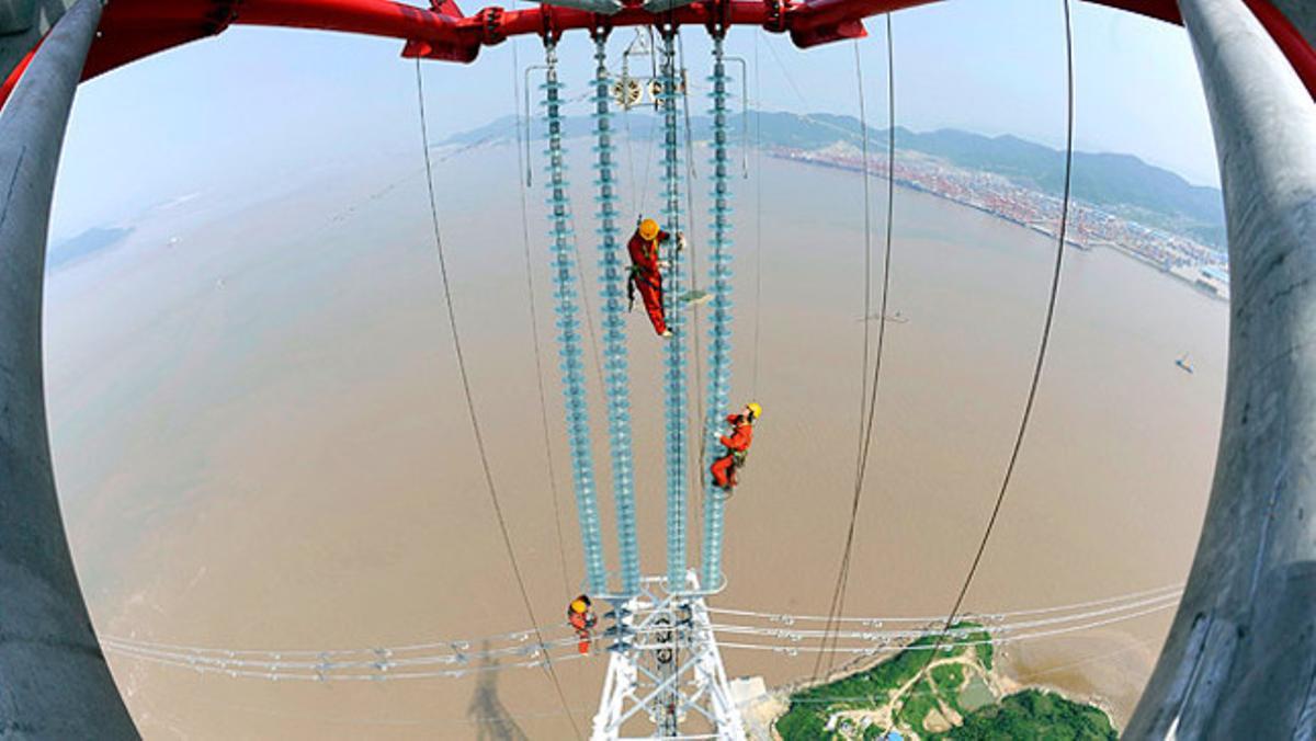 Un grup d’obrers escalen desenes de metres per reparar el cablejat elèctric d’una planta d’energia a Hangzhou (Xina).