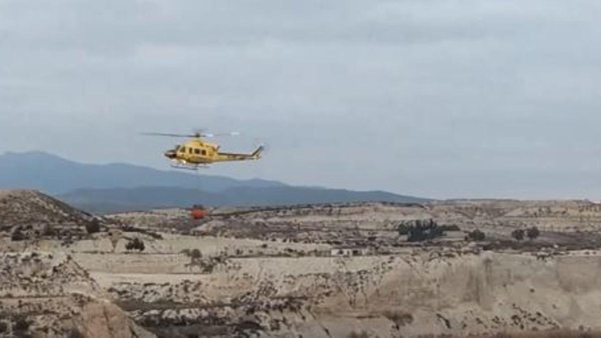 El helicóptero vierte agua sobre la zona de Albudeite.
