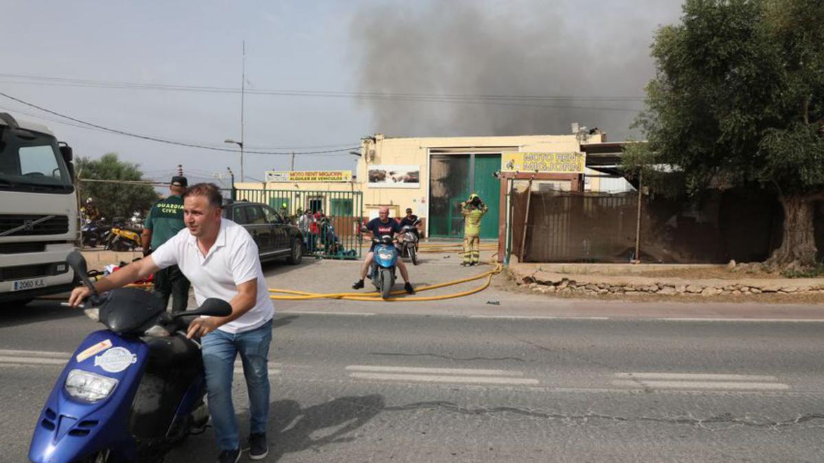 Vecinos de la zona industrial ayudan a sacar motos situadas en el exterior de la nave.