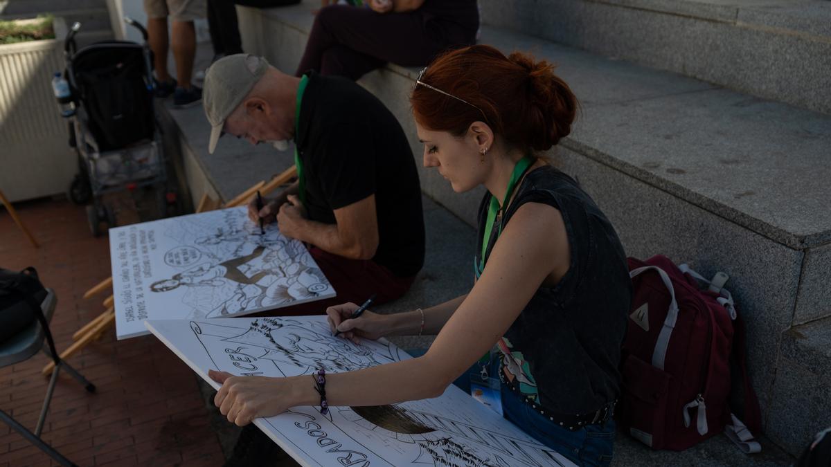 Dos de los artistas dibujan sus viñetas en la plaza de Santa maría.