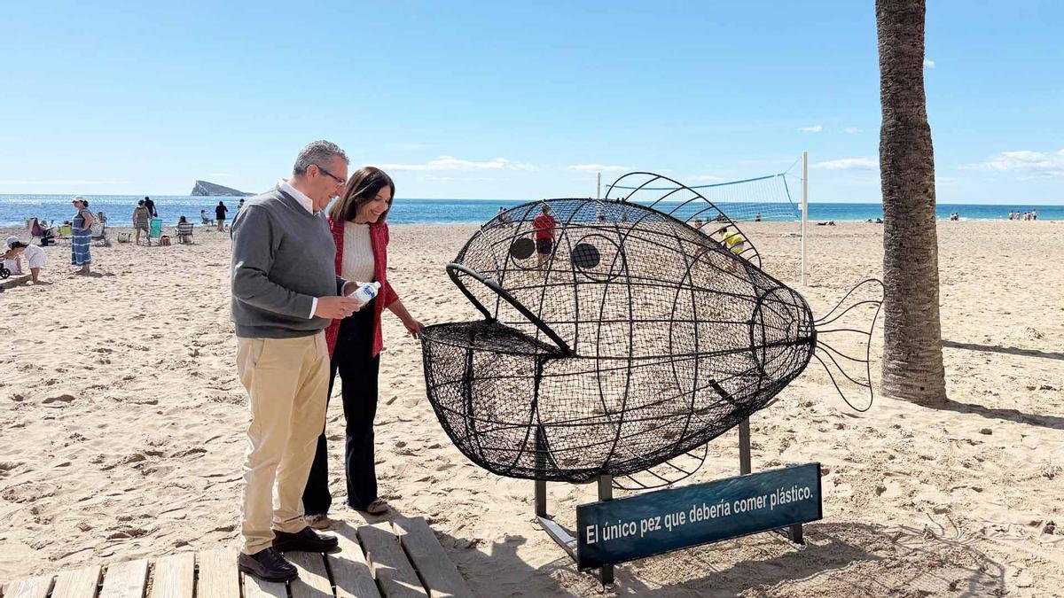 La obra instalada en la playa de Poniente para fomentar el reciclaje, con el alcalde y la edil de Playas