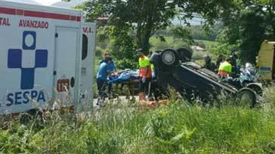 La evacuación del herido, con el coche aún volcado en la carretera.