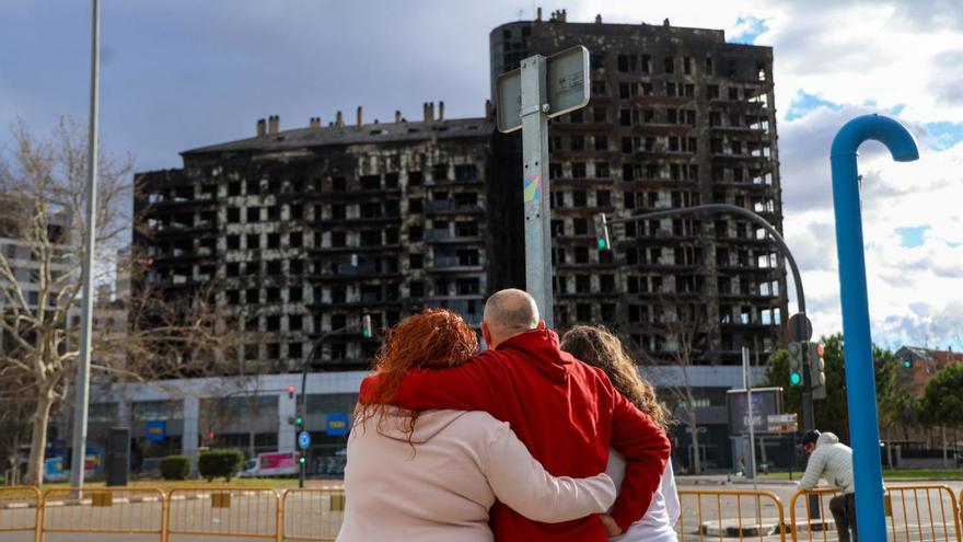 Una familia observa el edificio quemado desde una de las avenidas contiguas, ayer.  | F.CALABUIG