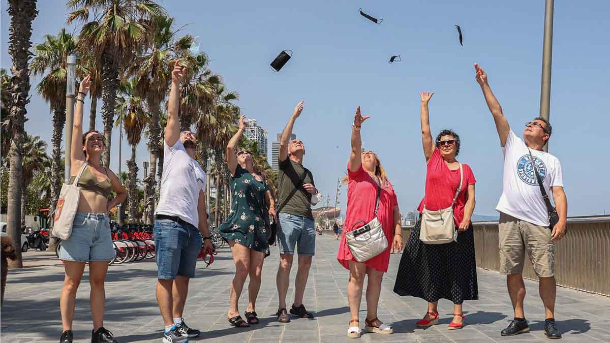 Un grupo de gente en el paseo Marítim de Barcelona lanza sus mascarillas al aire