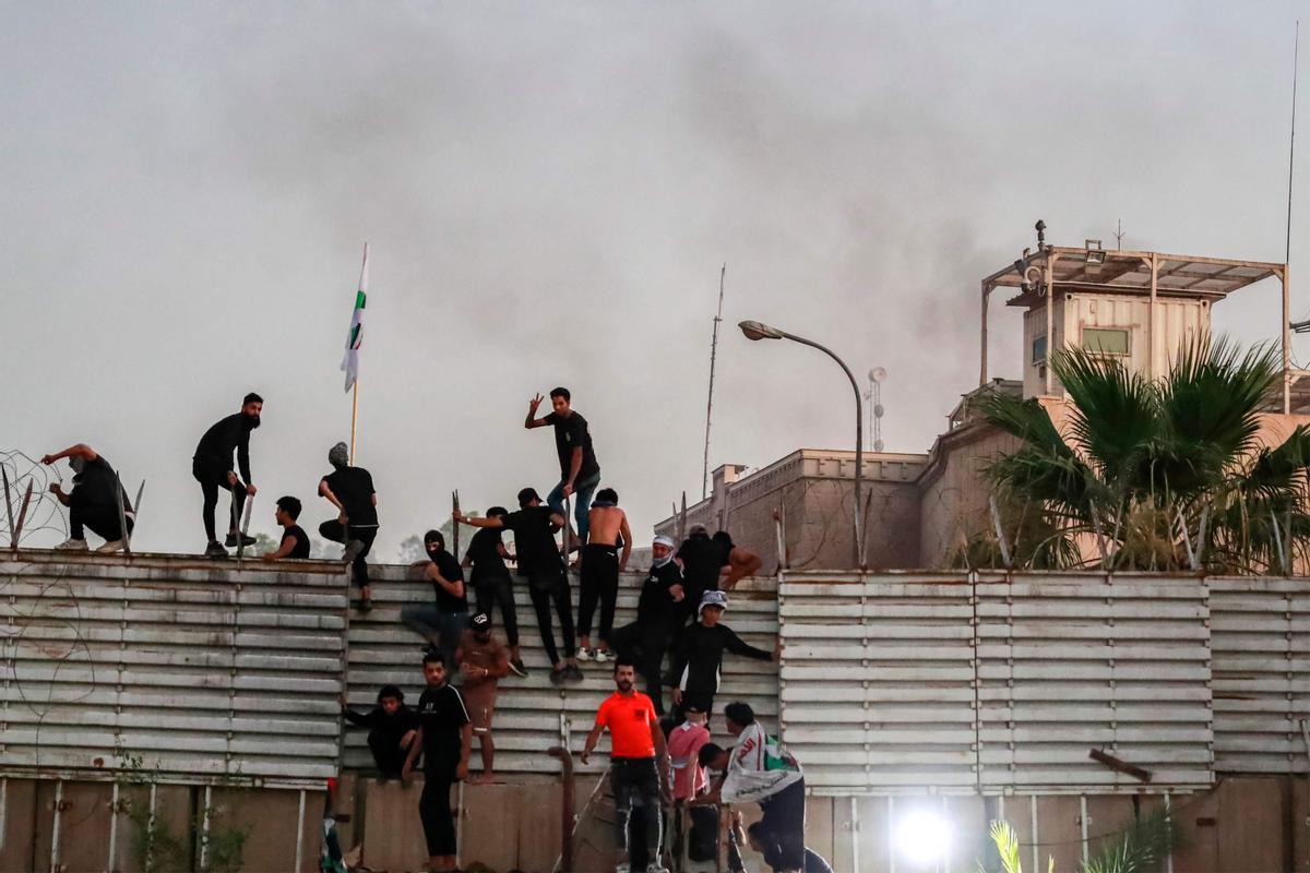 Los partidarios del clérigo chiíta iraquí Moqtada al-Sadr escalan la valla frente a la embajada sueca en Bagdad.