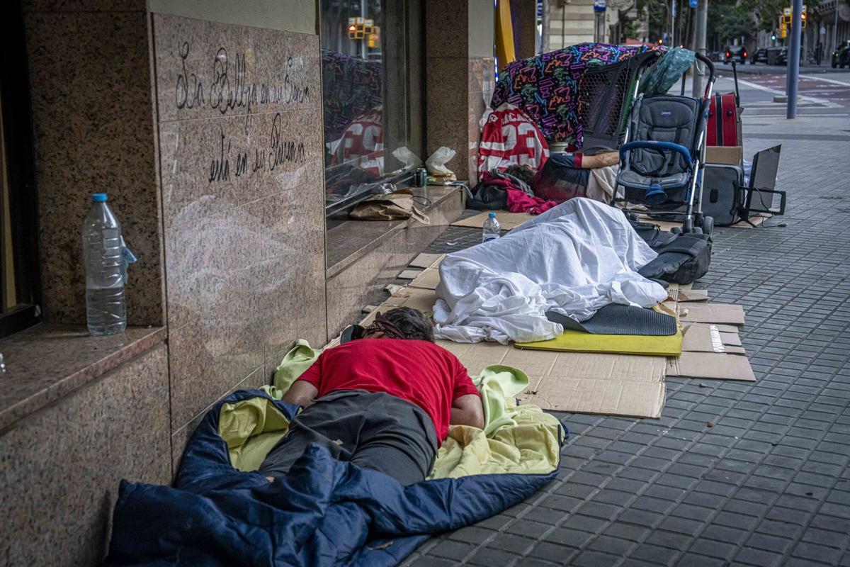 Personas duermen en la calle sobre colchones junto a comercios de la zona de Trafalgar-Méndez Núñez, a primera hora de la mañana este agosto