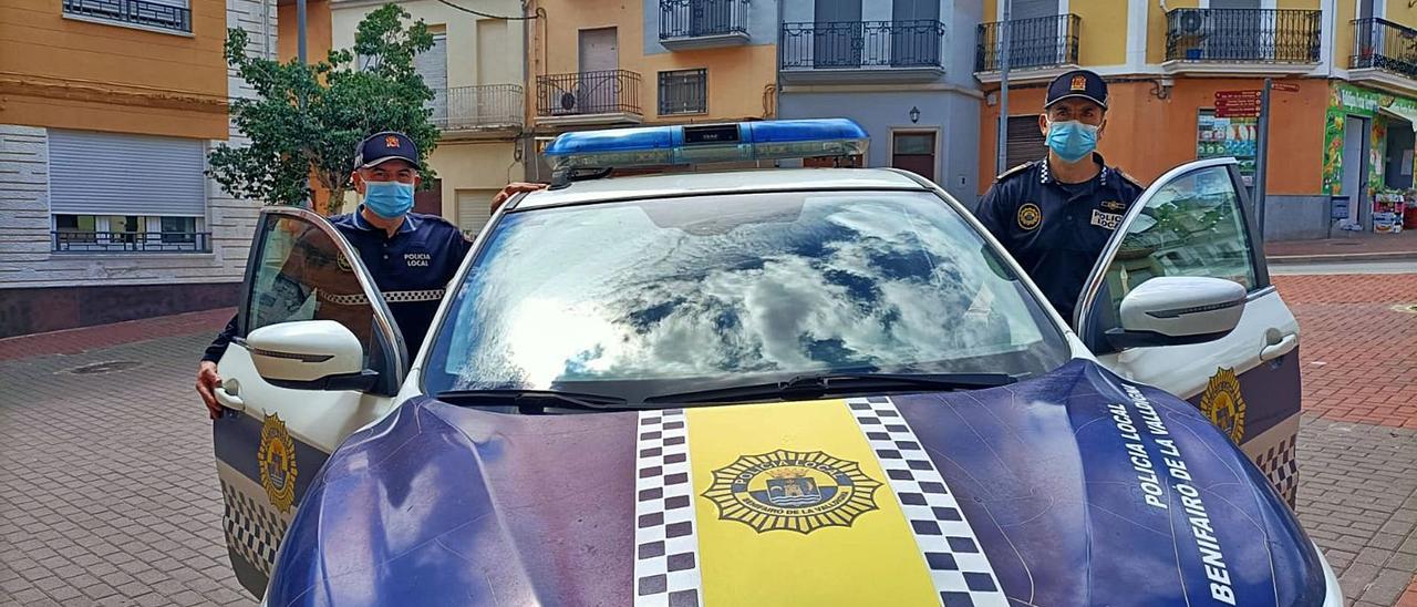 Un agente de Simat y otro de Benifairó suben al coche patrulla, ayer ante el consistorio simatero. | LEVANTE-EMV