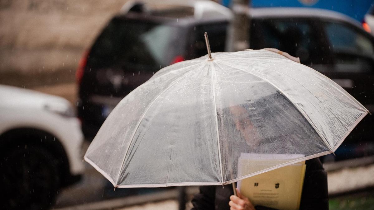Archivo - Una persona se protege de la lluvia con paraguas.