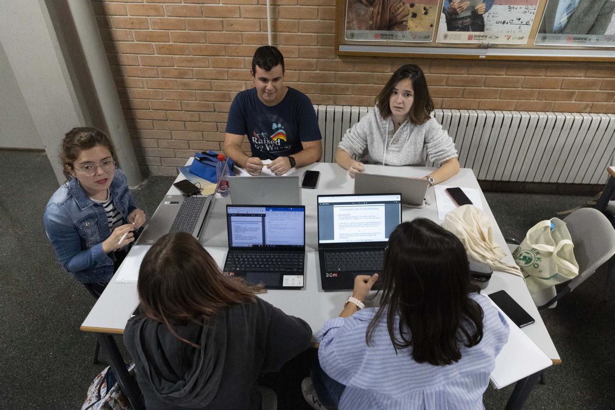 Varios alumnos universitarios con un portátil en clase.