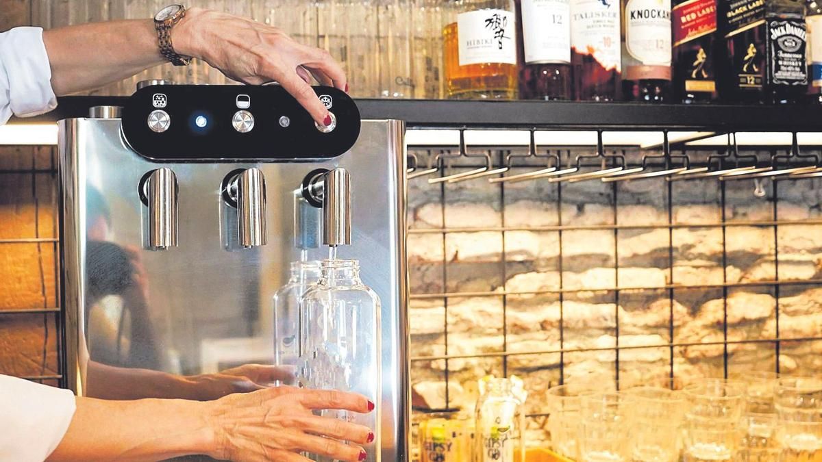 Una cambrera omple una ampolla d'aigua purificada en un restaurant del centre de Madrid