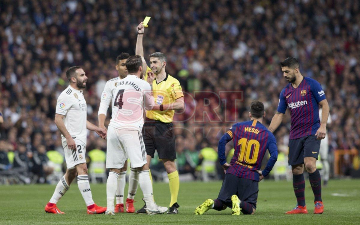 El árbitro Undiano Mallenco saca la tarjeta amarilla a Sergio Ramos por juego peligroso durante el partido entre el Real Madrid y el FC Barcelona en el Estadio Santiago Bernabéu de jornada 26 de La Liga.