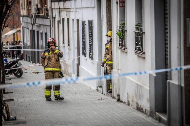 Dos bomberos ante la puerta del bloque parcialmente derrumbado el 6 de febrero en la calle Canigó de Badalona