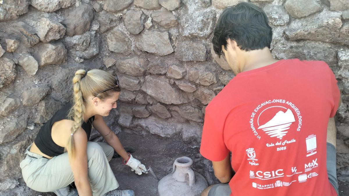 Dos jóvenes realizan una excavacion arqueológica.
