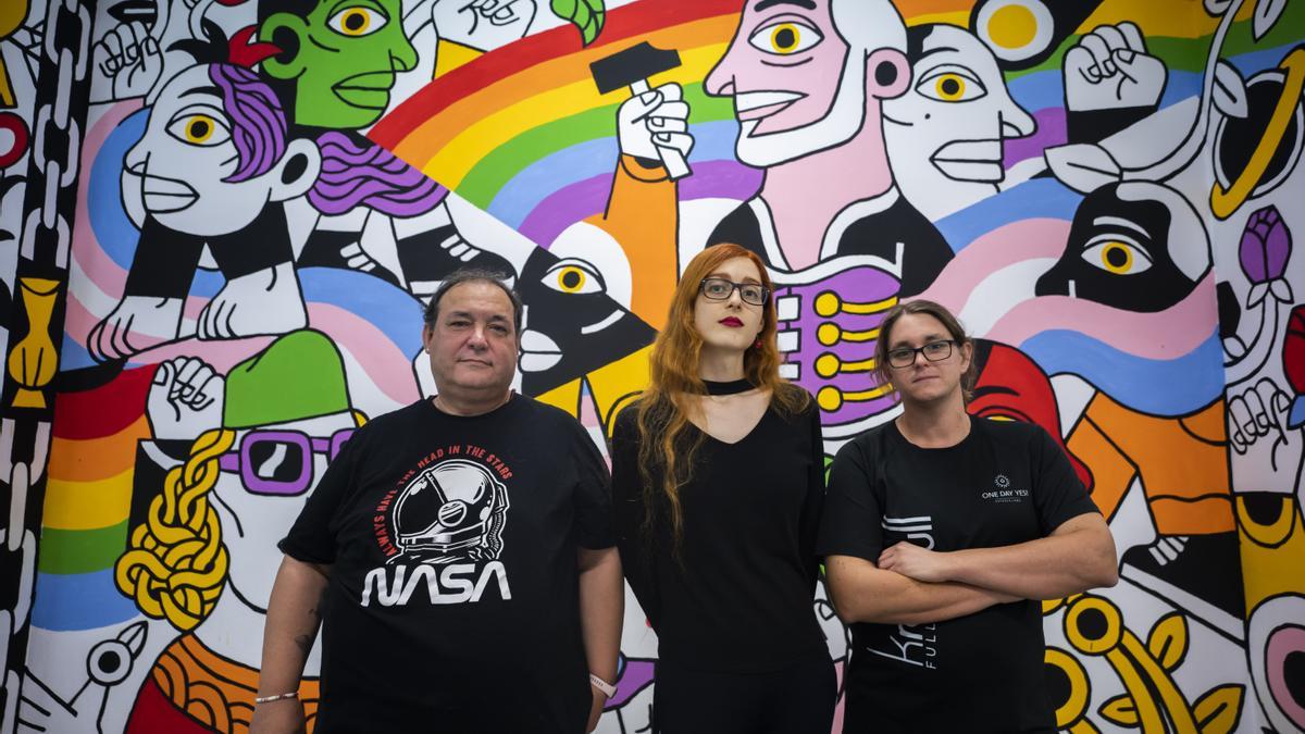 Naiara, Raquel y Nhabi frente a un mural en la sede de Lambda en València.