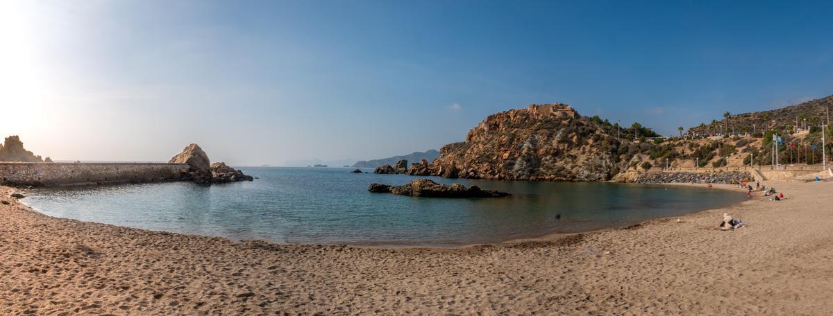 Cala Cortina, una hermosa cala con una playa de arena en forma de herradura rodeada de fortalezas históricas
