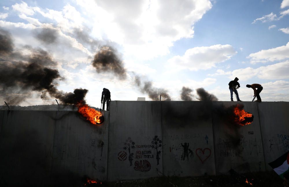 Manifestantes palestinos queman neumáticos en una sección de la frontera israelí, durante unos enfrentamientos en el duodécimo aniversario de su campaña contra el muro.