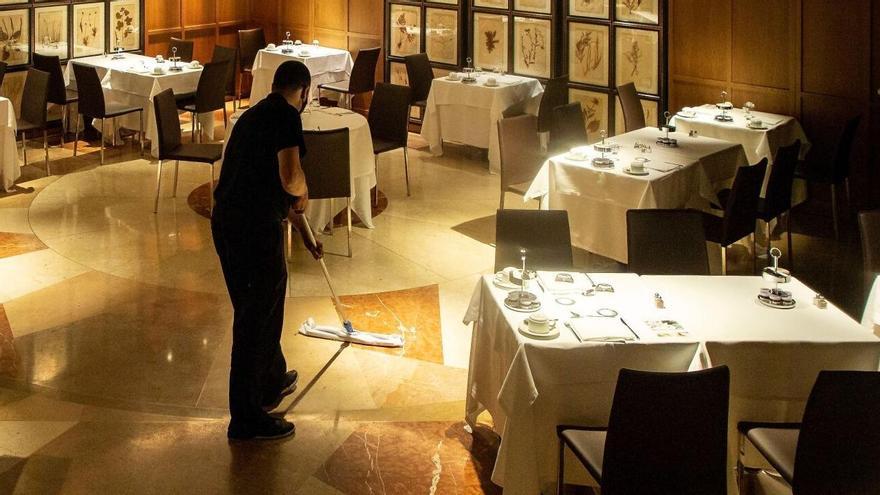 Un empleado acondiciona una sala con mesas reservadas en un restaurante.