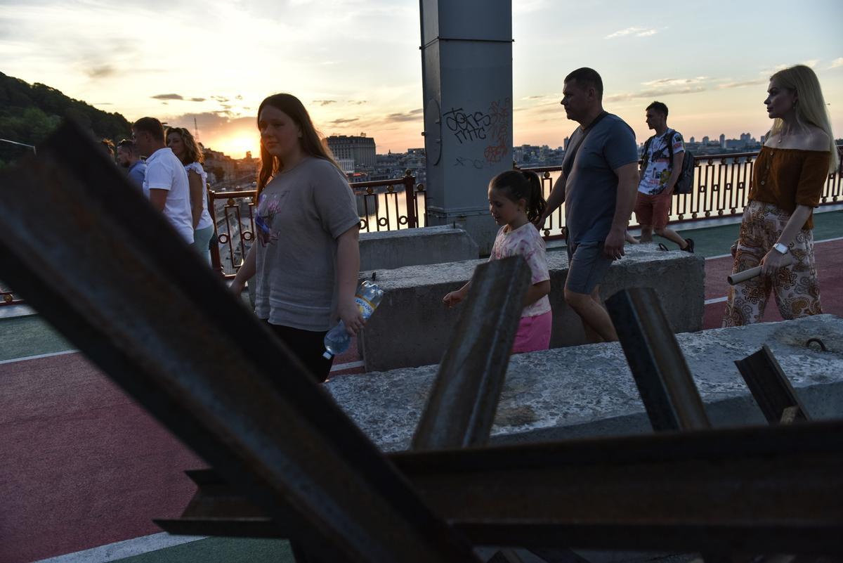 La gente cruza un puente peatonal sobre el río Dnipro en Kiev