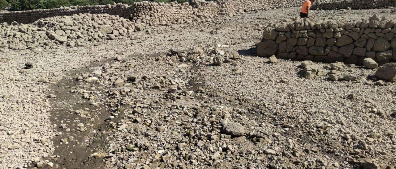 Zona que ha quedado al descubierto por la falta de agua en el embalse y donde se aprecia el canal por el cementerio.