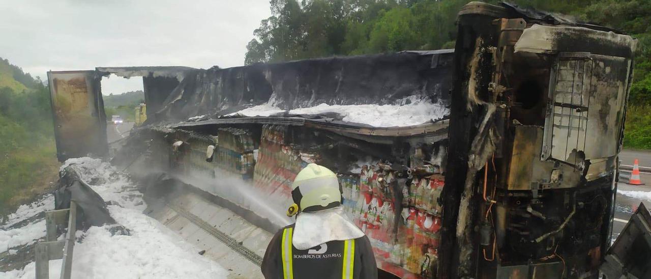 Los bomberos extinguen el fuego en el remolque del camión volcado antes del túnel de Llovio, en Ribadesella