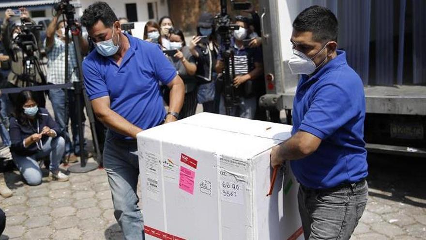 Dos hombres bajan de un camión una caja que contiene dosis de las vacunas contra la covid-19.