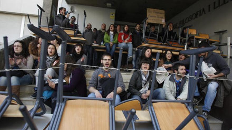 Una imagen de los miembros de l a Plataforma de Estudiantes tras las mesas y sillas que han instalado en la puerta del edificio de Geografía e Historia de la UA
