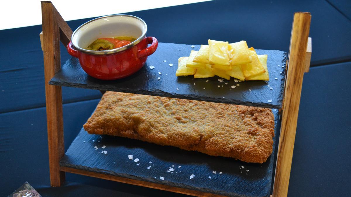 El cachopo de el restaurante La Escollera, de San Juan de La Arena, acompañado de patatas suflé y pimientos asados verdes y rojos.