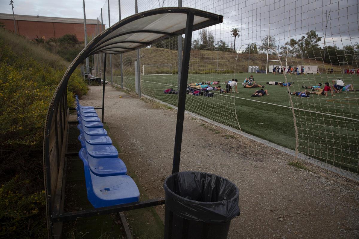 Un banquillo entre el campo de rugby y los hierbajos que crecen en el complejo de la Teixonera-Vall d'Hebron, en Barcelona.