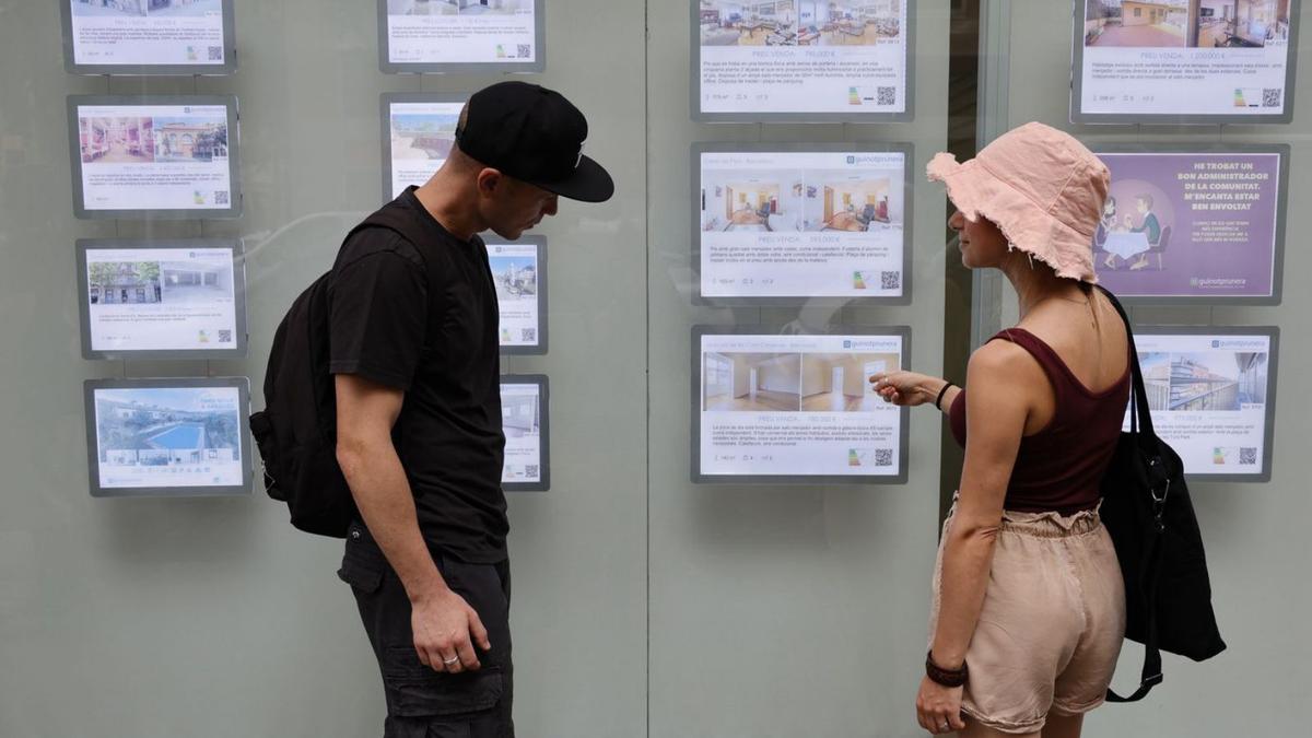 Una pareja consulta los precios de pisos de Barcelona en una inmobiliaria.