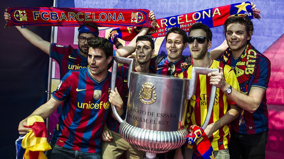 Un grupo de aficionados del Barça posan con una réplica de la Copa del Rey en Valencia