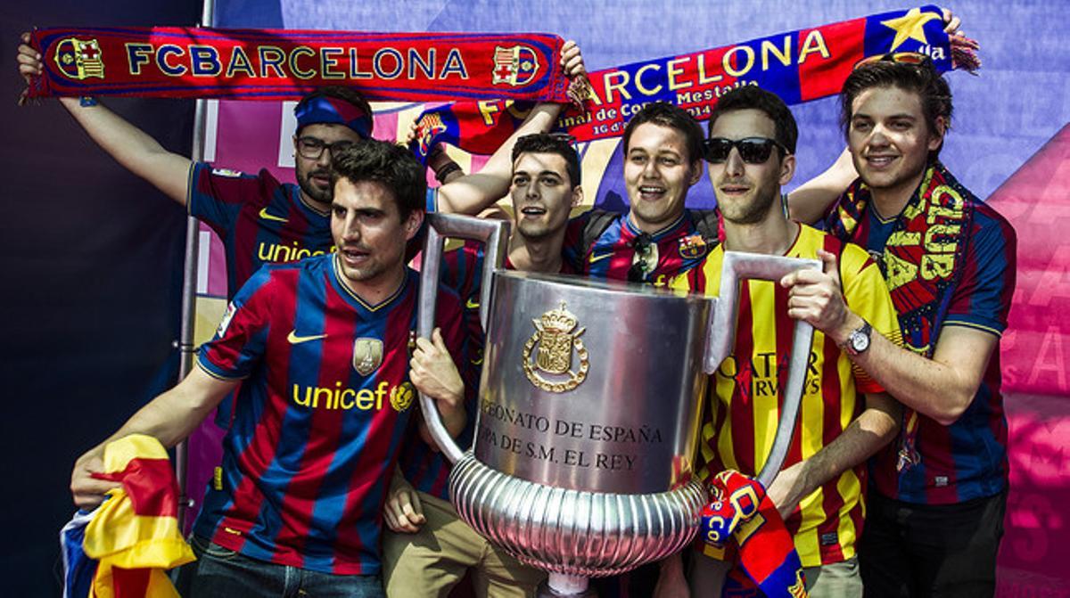 Un grup d’aficionats del Barça es fotografien amb una rèplica de la Copa del Rei a València.
