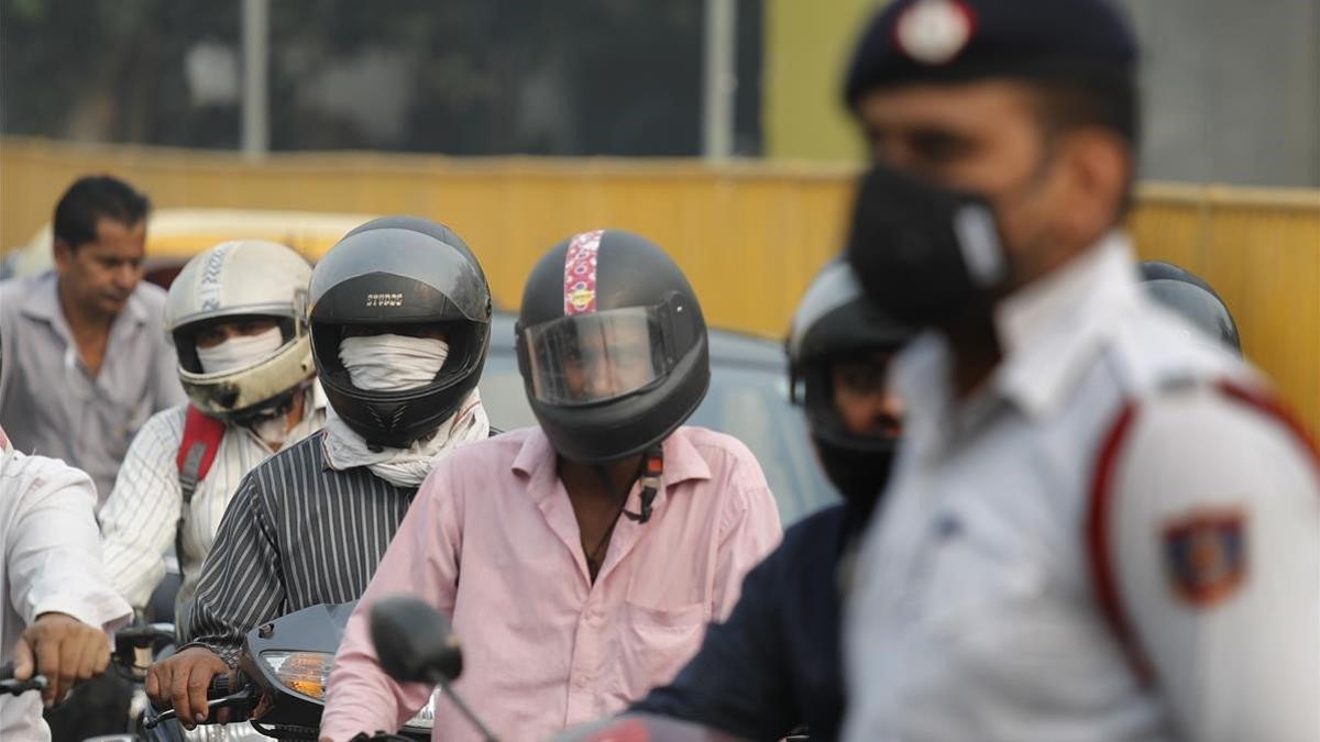Varios motoristas y un guardia se protegen con mascarillas de la elevada polución, este lunes en Nueva Deli.